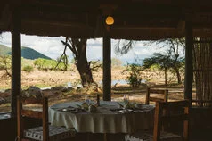 Tavolo apparecchiato al Ruaha River Lodge con vista sul paesaggio selvaggio di Ruaha
