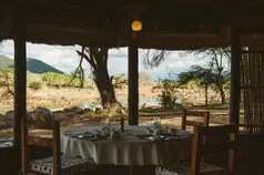 Tavolo apparecchiato al Ruaha River Lodge con vista sul paesaggio selvaggio di Ruaha
